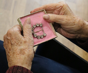 Image of a 1920's jewelled belt buckle being looked at by an elder gentleman.